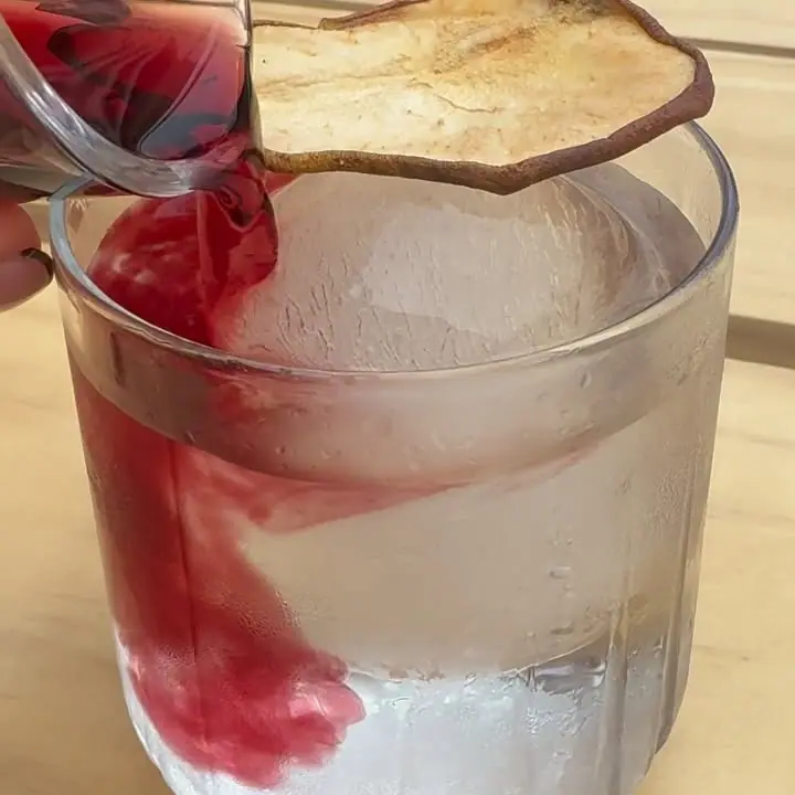 Cóctel transparente teñido de rojo por el vino tinto