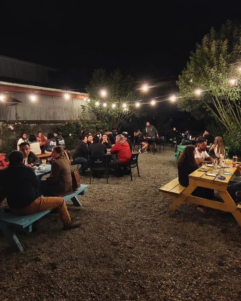 Terraza al aire libre de noche con guirnaldas de luces y mesas de madera