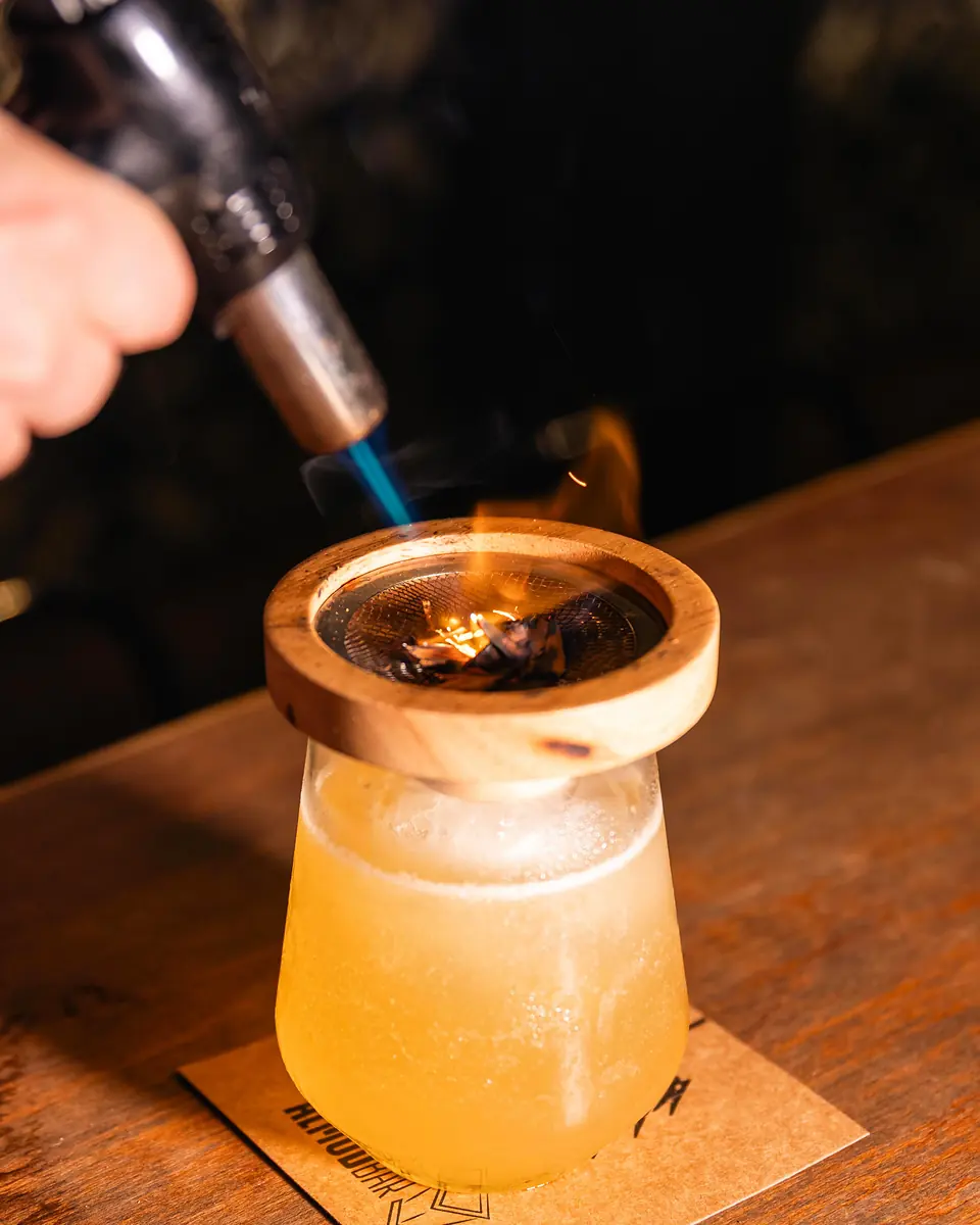 Vaso con humo saliendo bajo un ahumador, sobre un posavasos