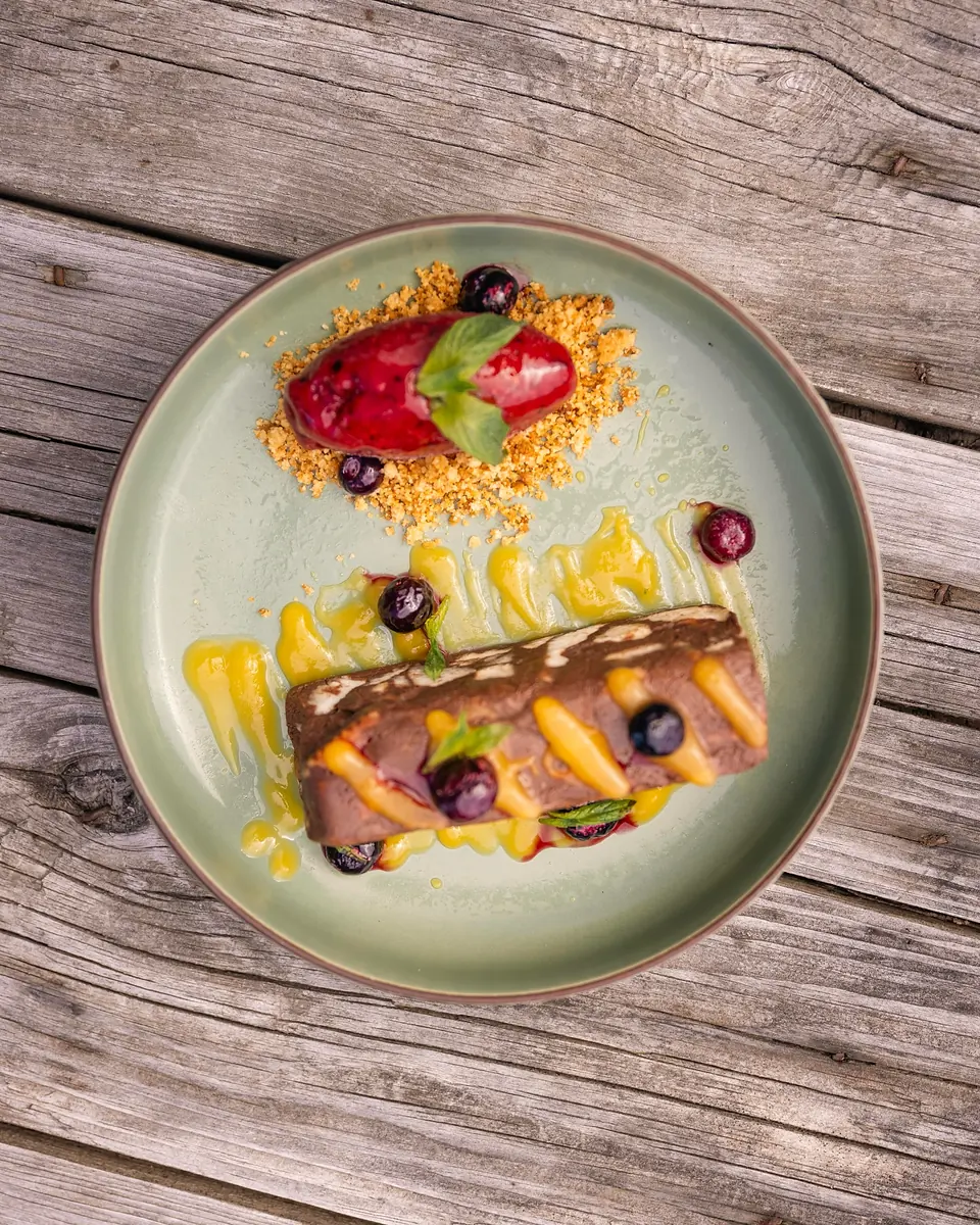 Postre de chocolate con frutos rojos en un plato verde sobre madera