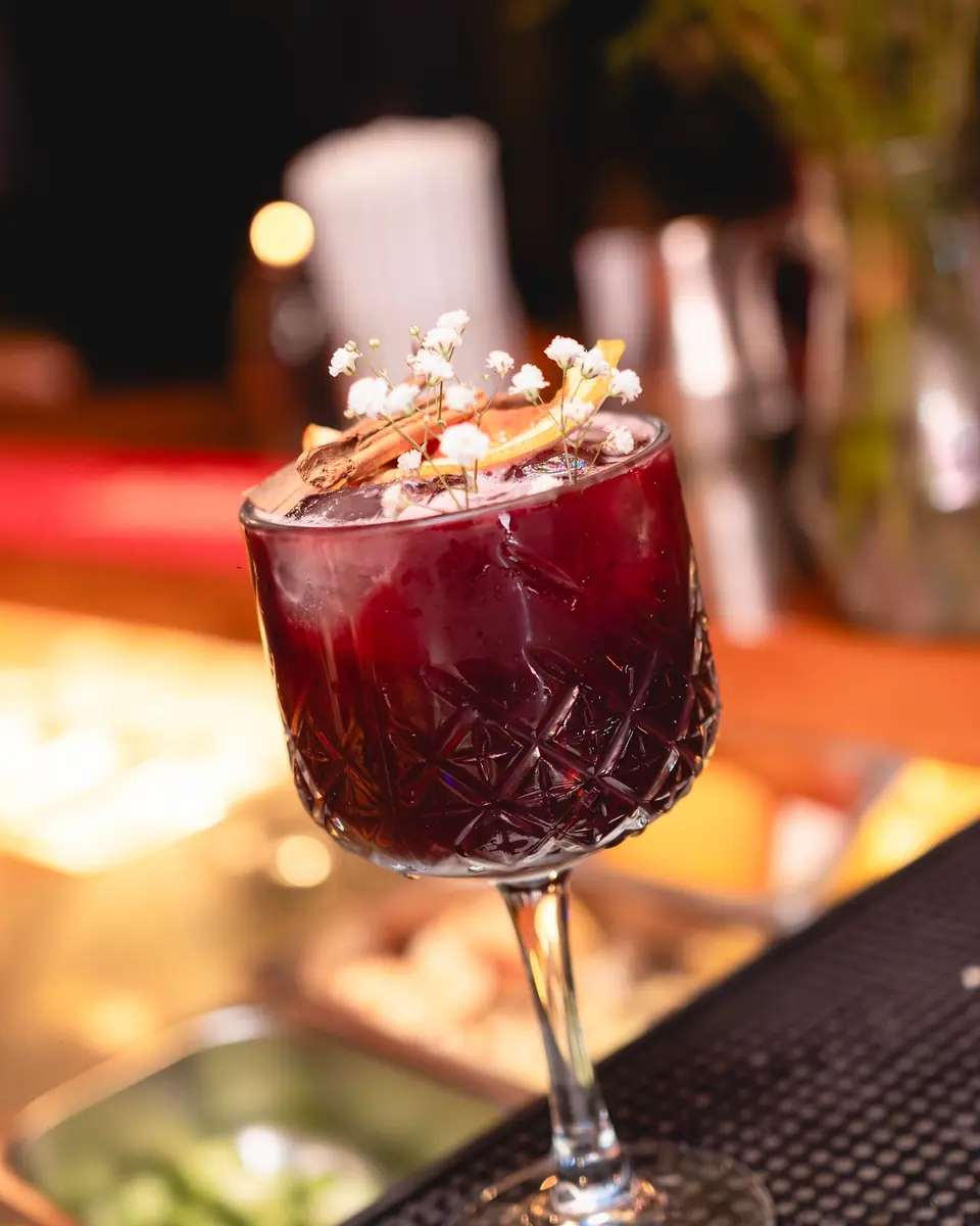 Copa tallada con sangría morada y una rama de canela sobre la barra