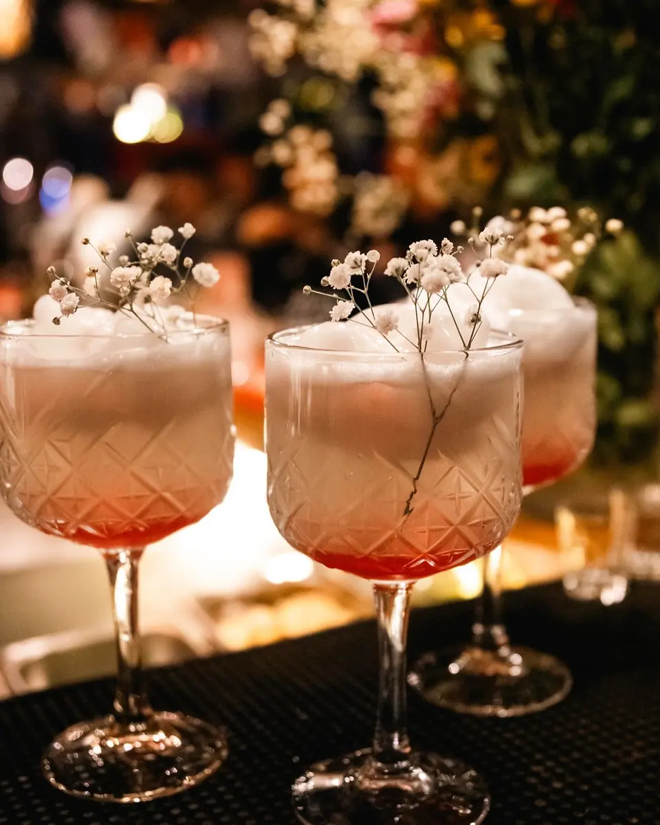 Tres copas talladas con espuma blanca y flores secas sobre la barra
